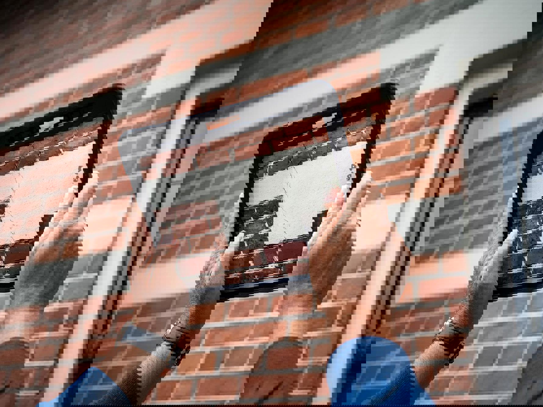 Met een tablet wordt een foto gemaakt van een scheur in een buitenmuur. 