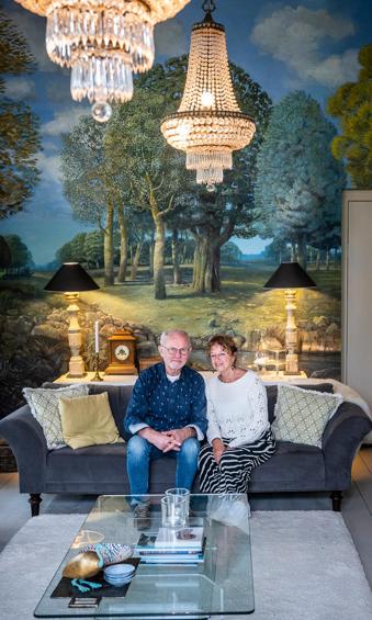Franke en Carola Koksma op de bank voor een muurschildering in de zitkamer.