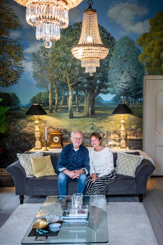 Franke en Carola Koksma op de bank voor een muurschildering in de zitkamer.
