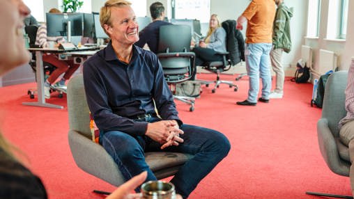 Teammanager in gesprek met collega's in de kantoortuin.
