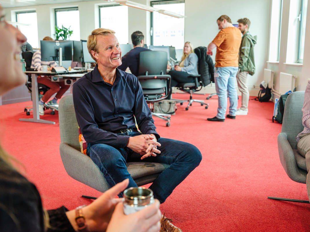 Teammanager in gesprek met collega's in de kantoortuin.