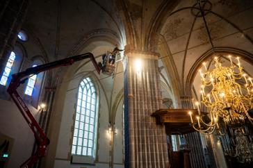 Een bouwkundig op een hoogwerker onderzoekt de gewelven van de Groningse Martinikerk