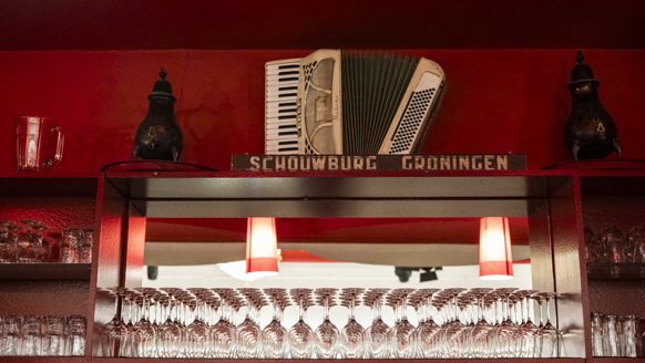 Een verlichte bar met muziekinstrumenten voor een rood geschilderde muur.