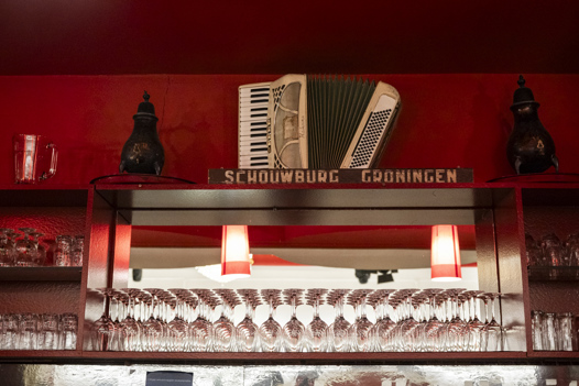 Een verlichte bar met muziekinstrumenten voor een rood geschilderde muur.