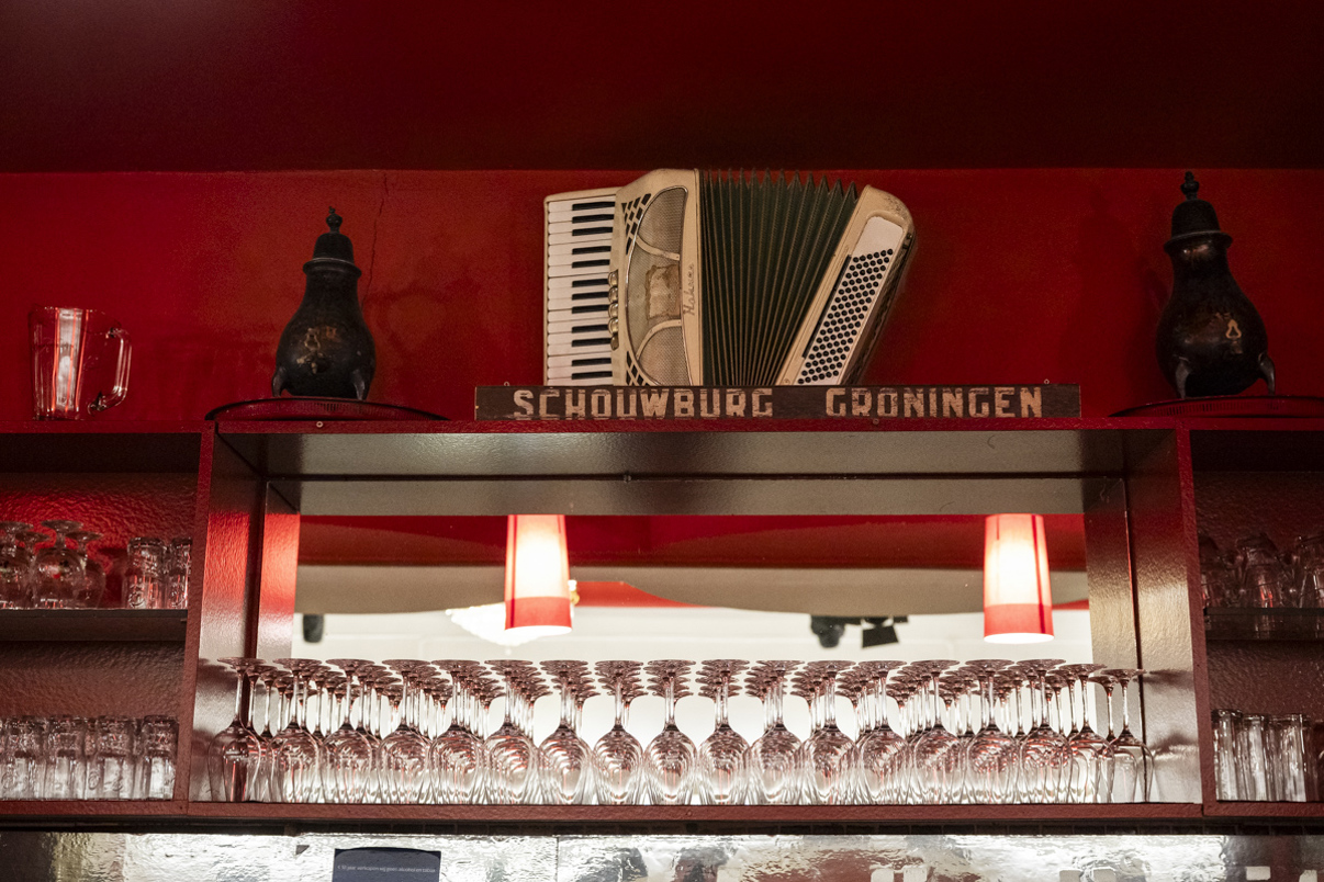 Een verlichte bar met muziekinstrumenten voor een rood geschilderde muur.