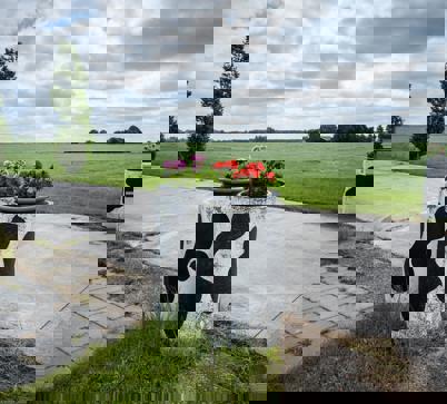 Een oprit tussen weilanden met bloempotten beschilderd met een koeienvlekpatroon.