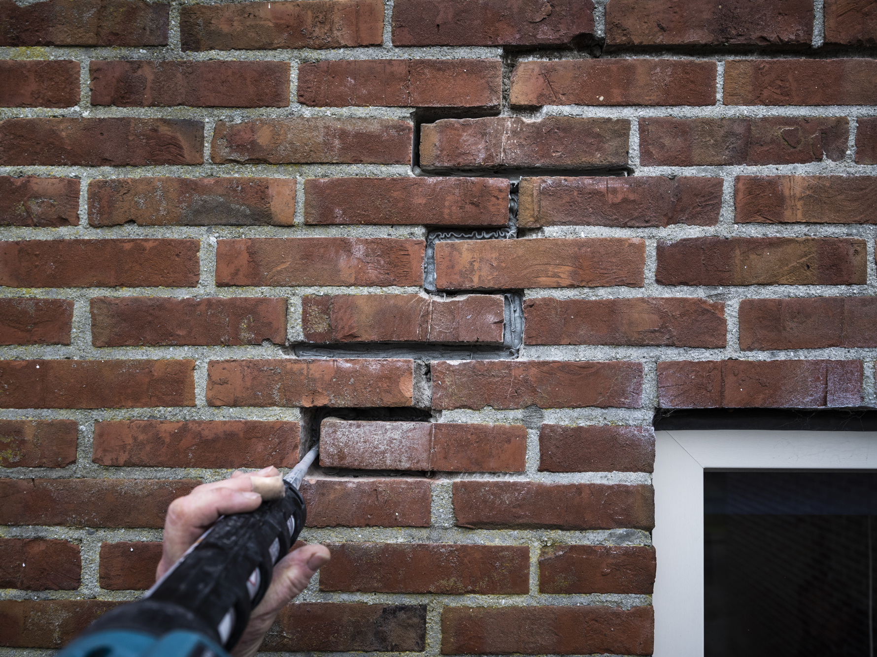 Een scheur in een buitenmuur wordt door een stukadoor hersteld.