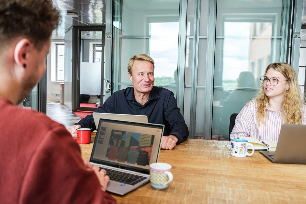 Teammanager en twee collega's in vergadering.