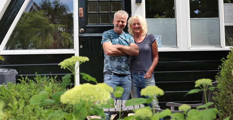 Helga en Pieter de Jong staan samen lachend in de tuin achter hun huis