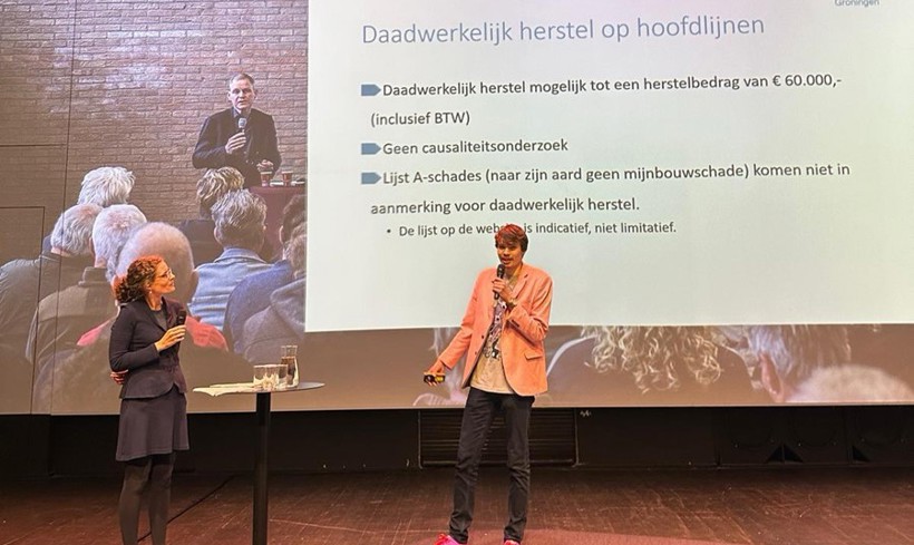 Twee mensen staan op een podium te presenteren