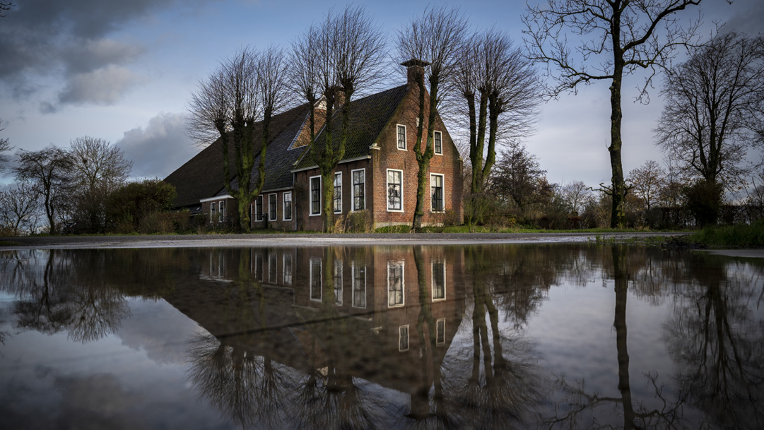 Zicht op Michiels door water omgeven boerderij in Tinallinge.
