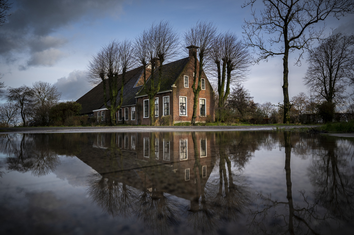 Zicht op Michiels door water omgeven boerderij in Tinallinge.