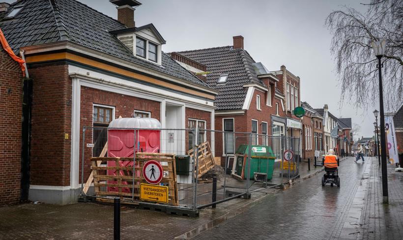 Straatbeeld in Loppersum, een dixi en bouwhekken versperren het voetpad.
