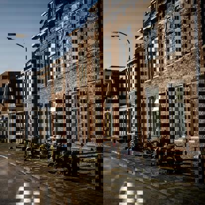 Een rij woningen in de zon met een blauwe lucht op de achtergrond.
