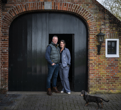 Linda Heuker en haar vriend voor de groene staldeur van hun rentenierswoning in 't Zandt