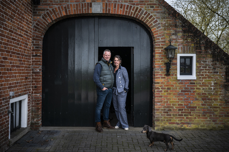 Linda Heuker en haar vriend voor de oude staldeur van hun huis.