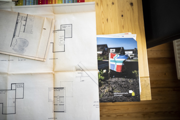 Op tafel liggen papieren waarop een bouwtekening van een woning zichtbaar is met erachter de map met documenten van Instituut Mijnbouwschade Groningen.