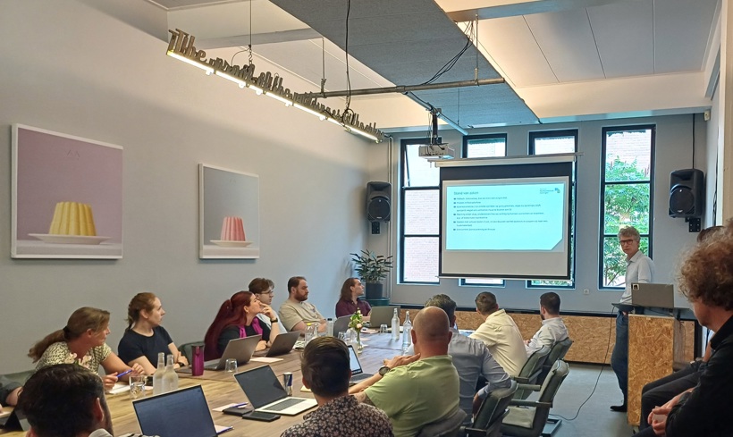 Team van ICT zit aan tafel en volgt presentatie