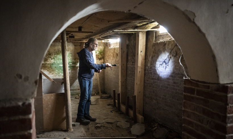 Peter schijnt met een zaklantaarn op de schade in de kelder van zijn huis.