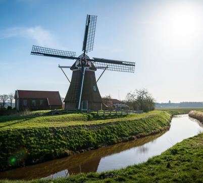 Een grote molen onder een zonnige, helderblauwe hemel.