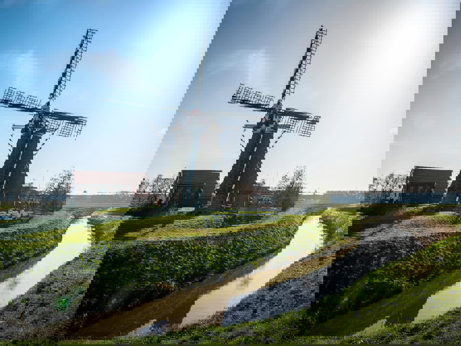 Een grote molen onder een zonnige, helderblauwe hemel.