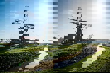 Een grote molen onder een zonnige, helderblauwe hemel.