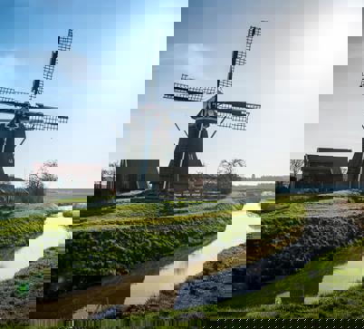 Een grote molen onder een zonnige, helderblauwe hemel.