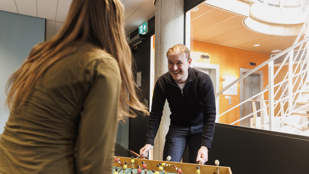 Niels speelt tafelvoetbal met een collega in de pantry.