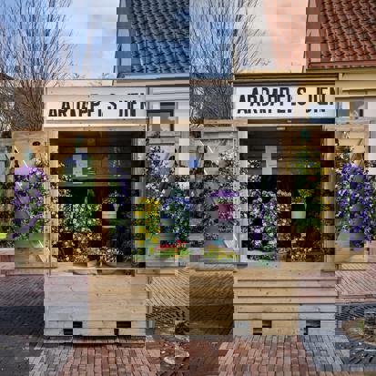 Een groentekraam waarin bloemen te koop worden aangeboden in een woonwijk.