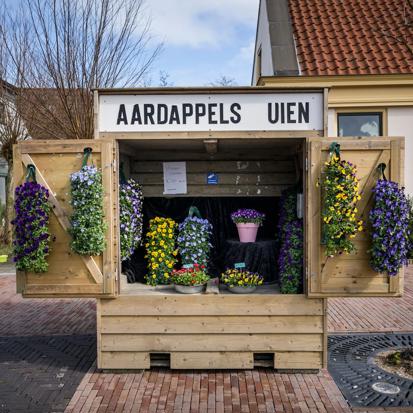 Een groentekraam waarin bloemen te koop worden aangeboden in een woonwijk.