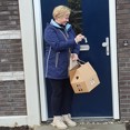 Jeanne Schoonhoven staat lachend met de sleutel in haar hand bij de voordeur van haar nieuwe woning