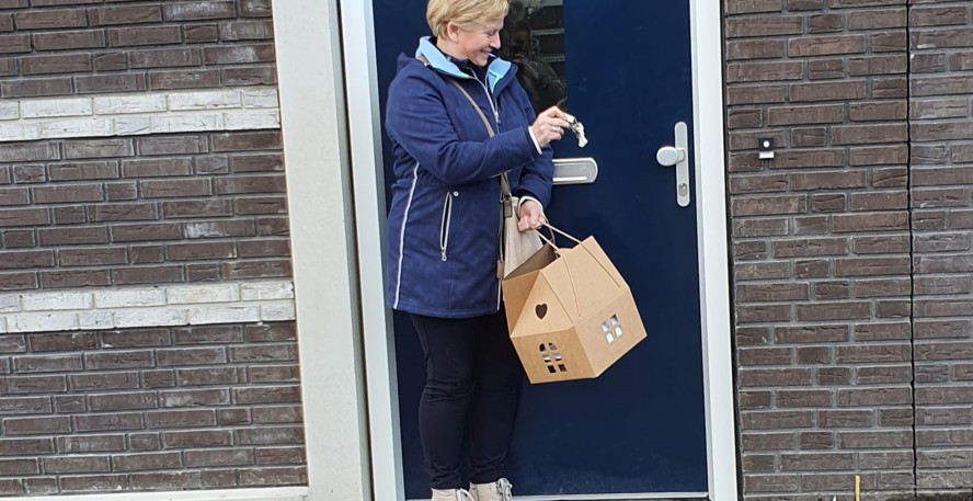 Jeanne Schoonhoven staat lachend met de sleutel in haar hand bij de voordeur van haar nieuwe woning