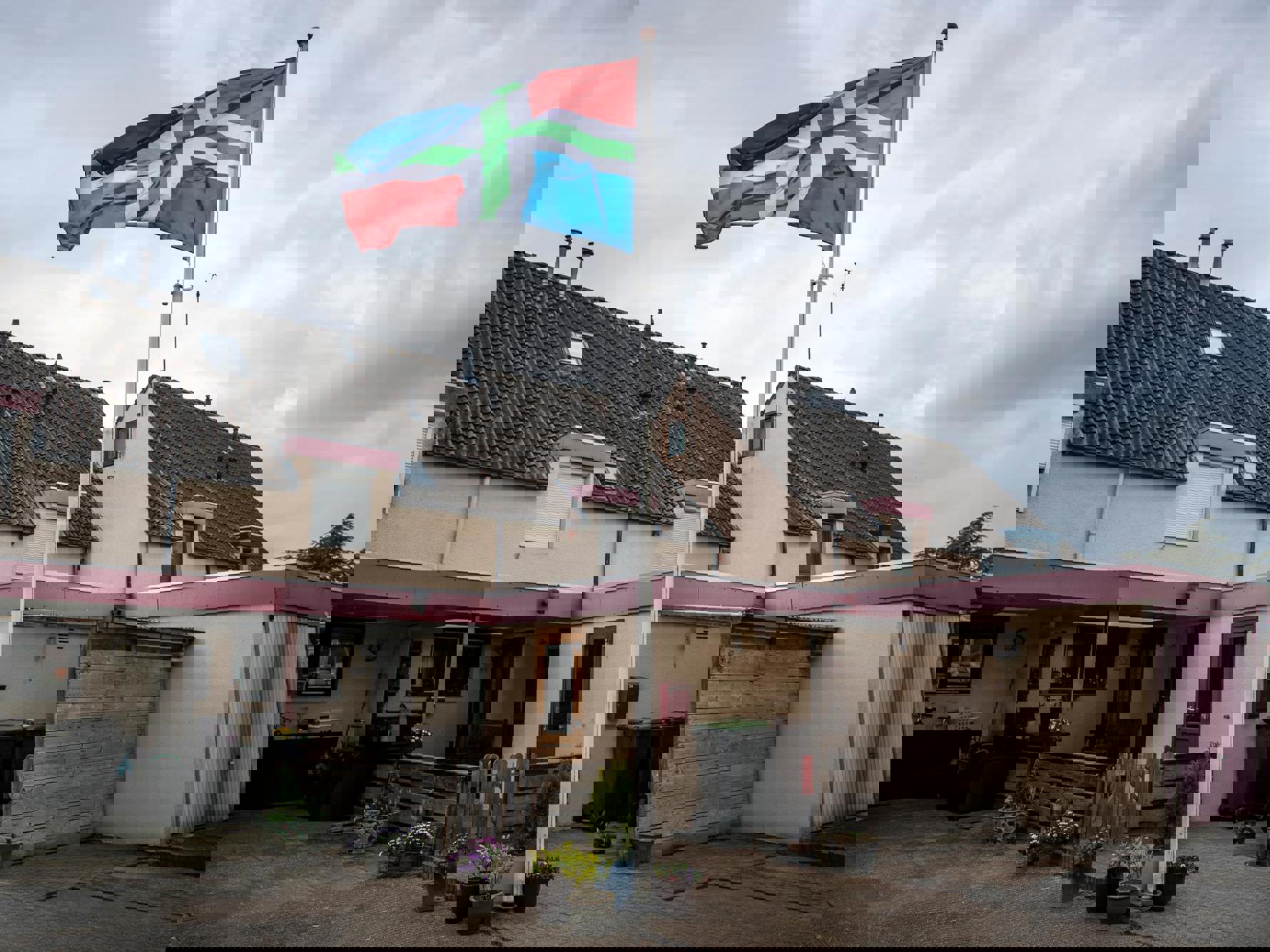 De Groningse vlag wappert bij een rij roze huizen in Sappemeer