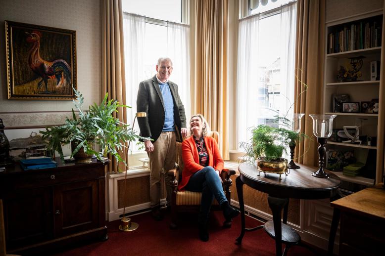 Joop en Erna Leffers zitten op een stoel in de woonkamer van hun huis.