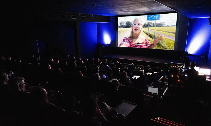 Een volle bioscoopzaal kijkt naar de video van een jongere over wonen in het Groningse aardbevingsgebied.