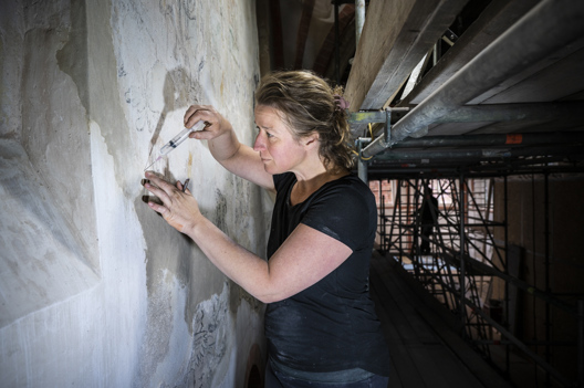 Restauratieschilder Aafje aan het werk in de kerk.