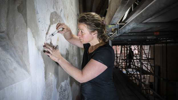 Restauratieschilder Aafje aan het werk in de kerk.