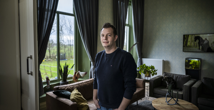 Dennis van der Leest in de woonkamer van zijn monumentale huis met diepe vensterbanken en leren meubels