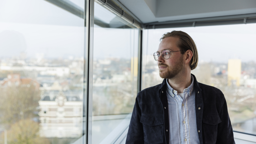 Jelle kijkt uit het raam met uitzicht op Groningen.