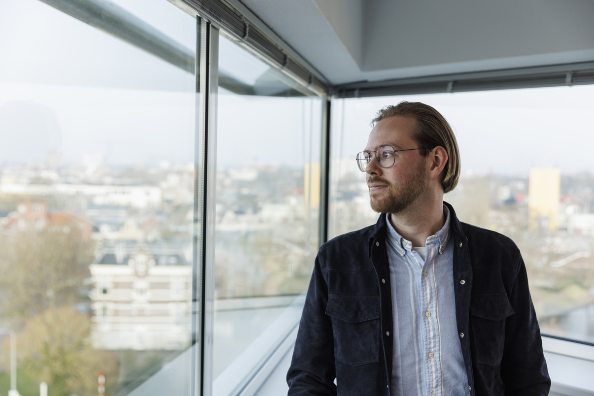 Jelle kijkt uit het raam met uitzicht op Groningen.