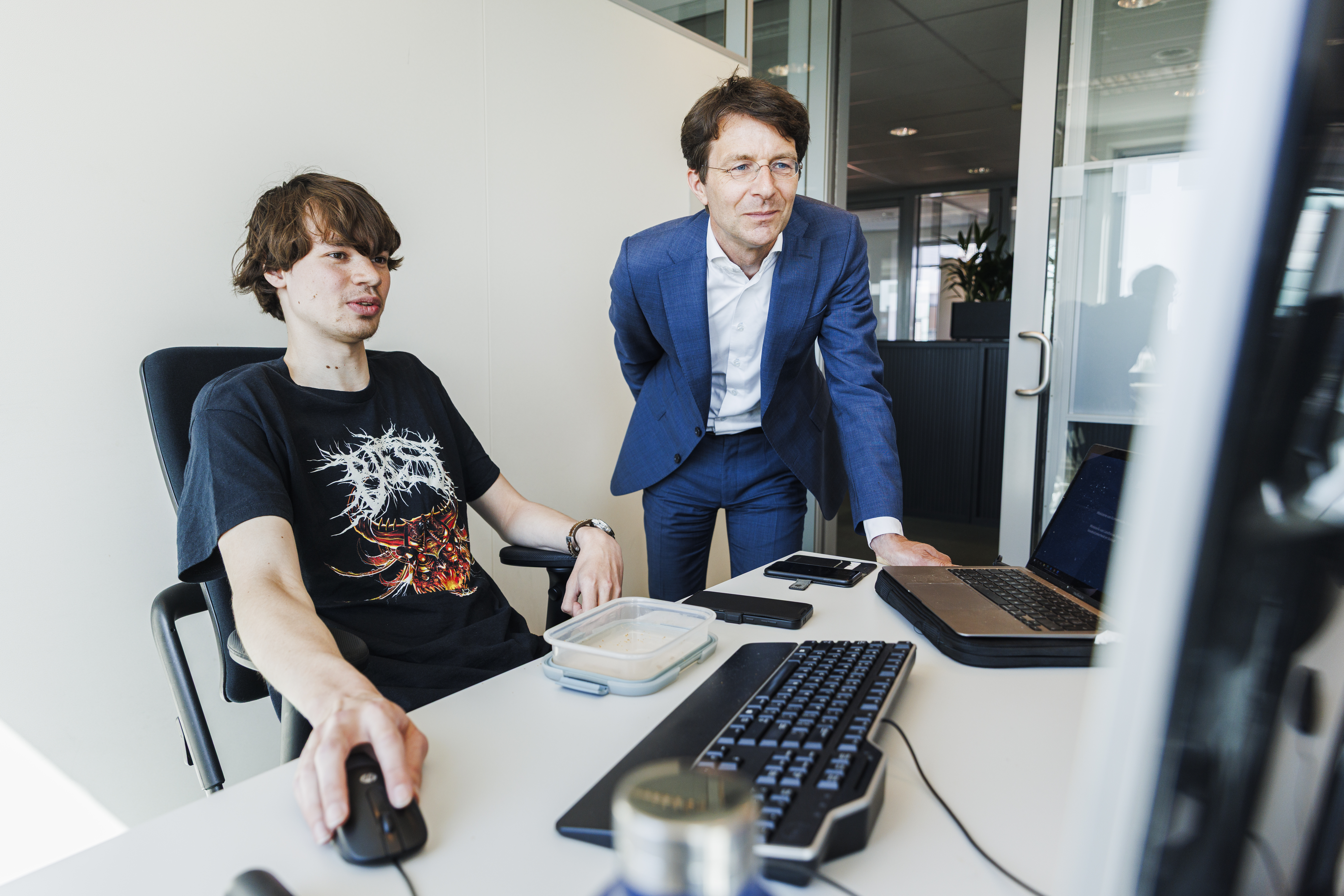 Ronald kijkt met een collega mee op de computer.
