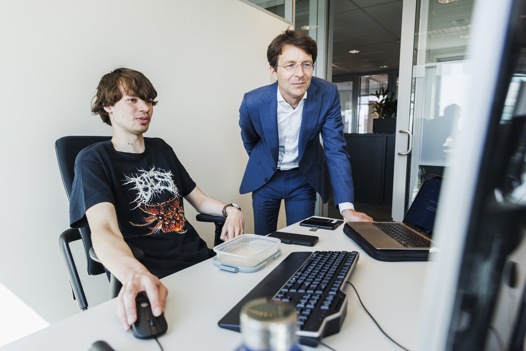 Ronald kijkt met een collega mee op de computer.